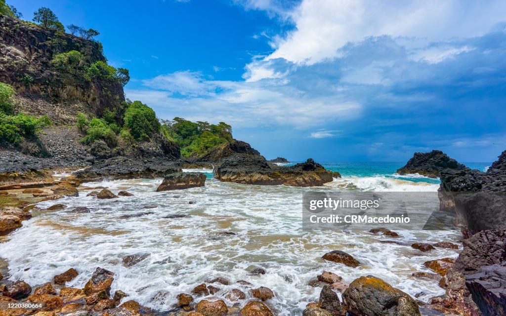 Bay of Pigs (Baia dos Porcos), in Fernando de Noronha. Volcanic stones, crystal clear sea with various shades of green in the background, and natural pools carved in the rocks.