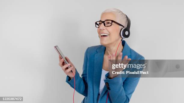 mulher sênior atraente positiva com fones de ouvido - idoso na internet - fotografias e filmes do acervo