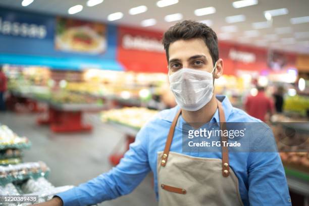 porträt eines jungen geschäftsmannes mit gesichtsmaske im supermarkt - essenzielle berufe und dienstleistungen stock-fotos und bilder