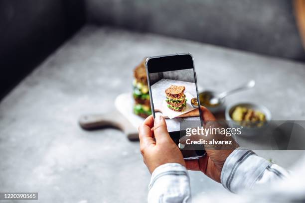 vrouw die veganistische supersandwich met zijn telefoon fotografeert - making a sandwich stockfoto's en -beelden