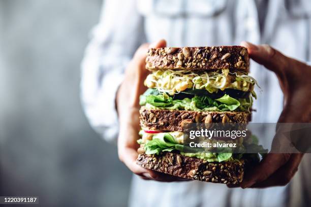 frauenhände halten ein großes vegetarisches sandwich - woman sandwich stock-fotos und bilder
