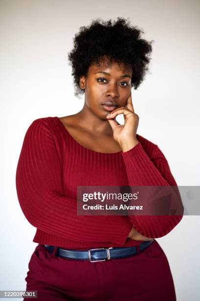 african american woman standing with her hand on chin - curvy black women stock-fotos und bilder