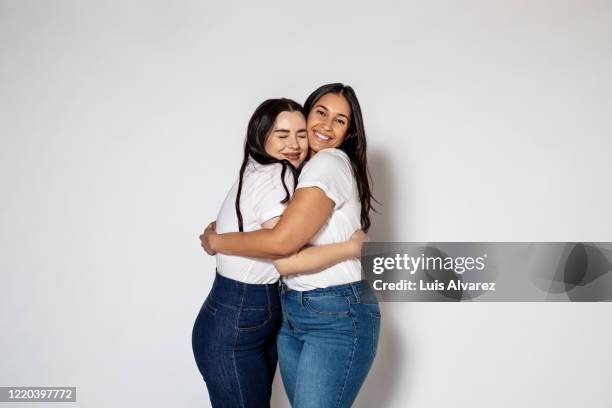 two female friends hugging each other - lichaamsbouw stockfoto's en -beelden