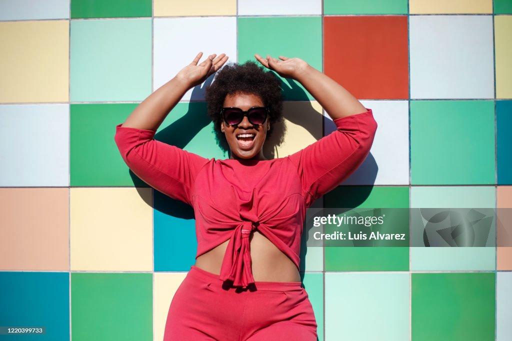 Stylish woman looking excited against multicolored tiled wall