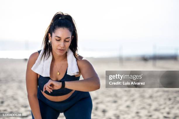 woman checking her fitness progress after workout at the beach - after run photos et images de collection