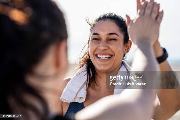 smiling woman giving high five to her friend after exercising - zelfvertrouwen stockfoto's en -beelden