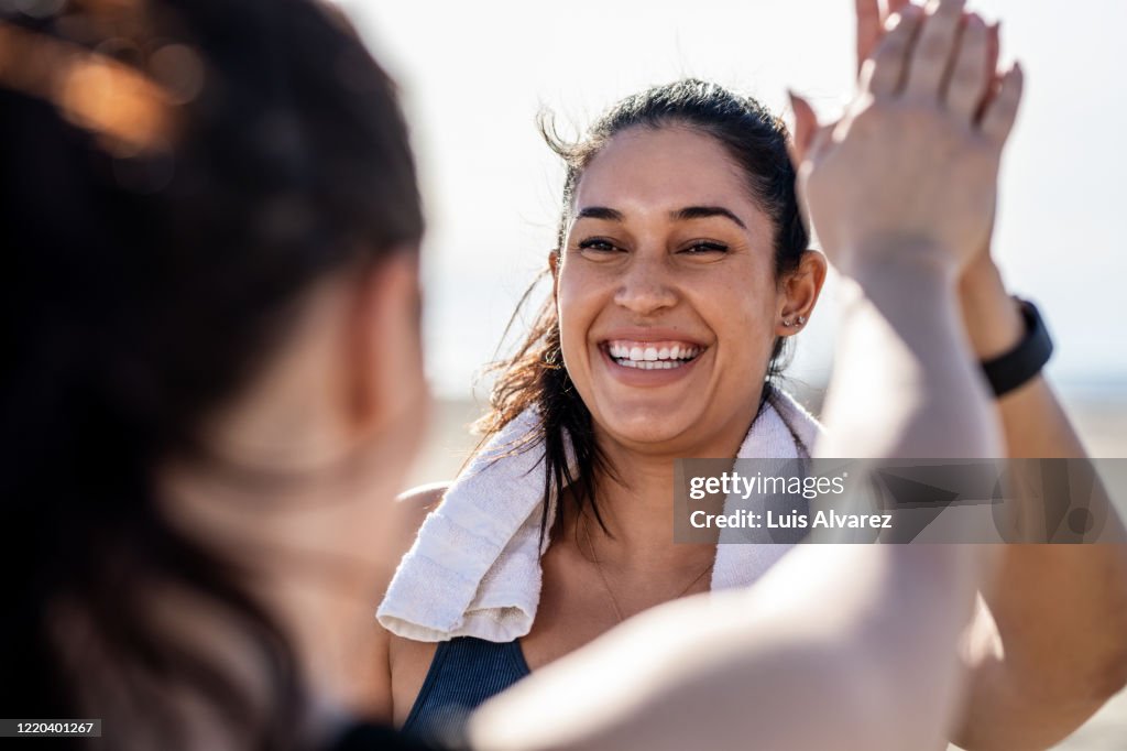 Smiling woman giving high five to her friend after exercising