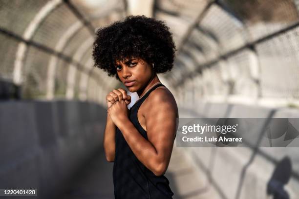 determined athletic woman in boxing stance - irréductibilité photos et images de collection