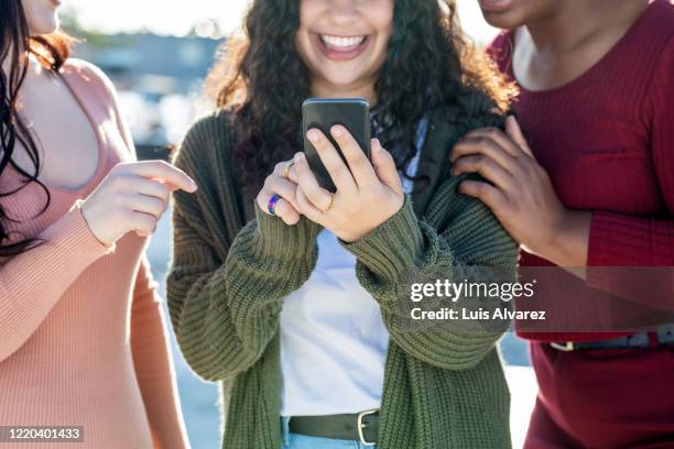 group of female friends using a mobile phone together - media day fotografías e imágenes de stock