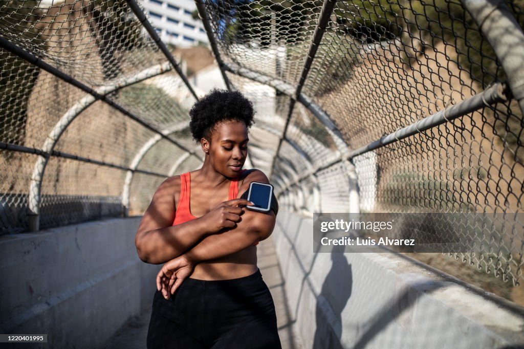 Healthy woman using phone on armband before exercising