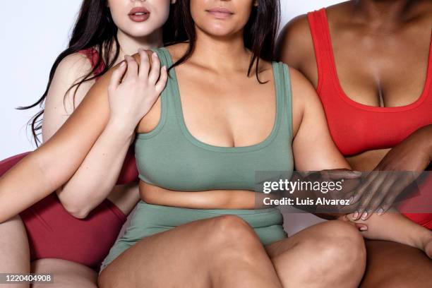 plus size women in underwear sitting close to each other - bra stockfoto's en -beelden