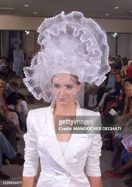 Un mannequin présente un tailleur de mariée blanc avec chapeau en dentelle, le 15 octobre 1999 à Paris, dans le cadre du salon "Oui au Mariage" qui...