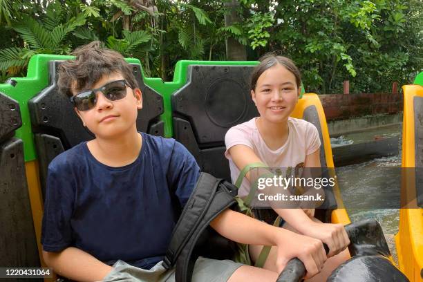 portrait of happy sibling enjoying water ride at amusement park. - theme park singapore stock pictures, royalty-free photos & images