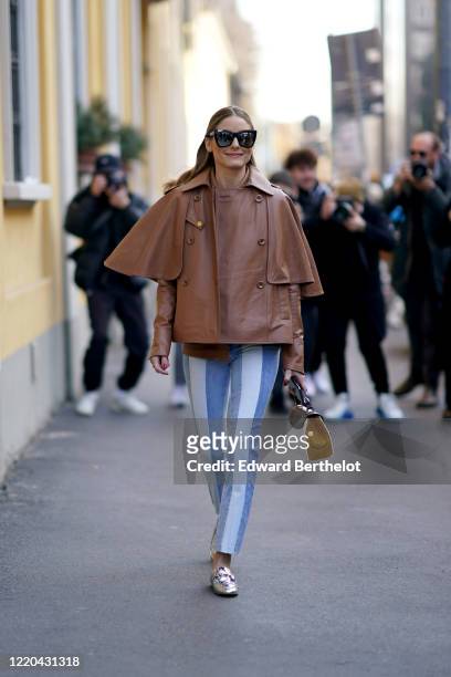 Olivia Palermo wears mirror sunglasses, a brown leather jacket, blue and white striped pants, a bag, silver shiny shoes, outside Tod's, during Milan...