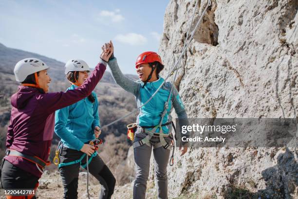 klimmers geven high fives na succesvolle finish klim - climbers stockfoto's en -beelden