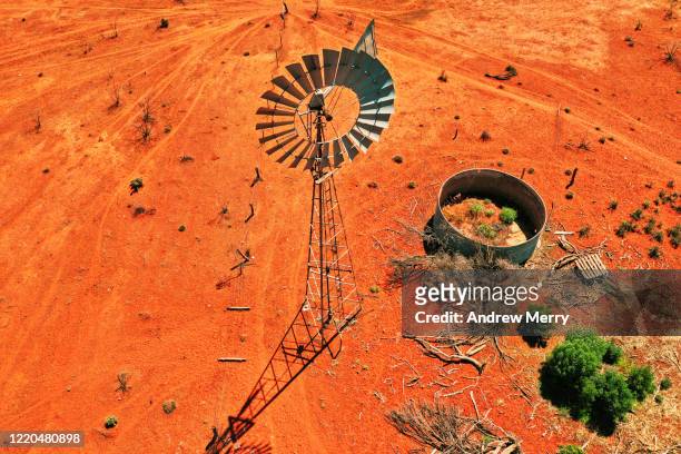 windmill, windpump and empty water storage tank on farm with red dirt field, australia, aerial view - outback windmill bildbanksfoton och bilder