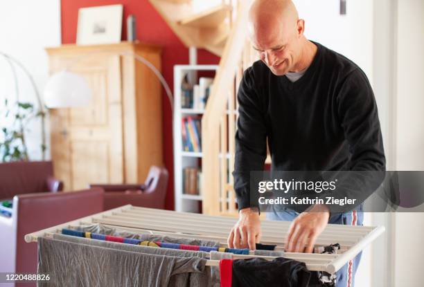 man hanging laundry on clothes drying rack - corde à linge photos et images de collection