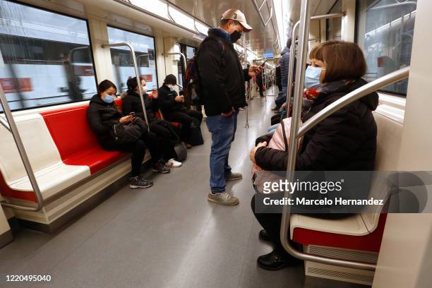 People wearing face masks ride the subway as the underground train continues to operate with a low flow of passengers due to the coronavirus pandemic...