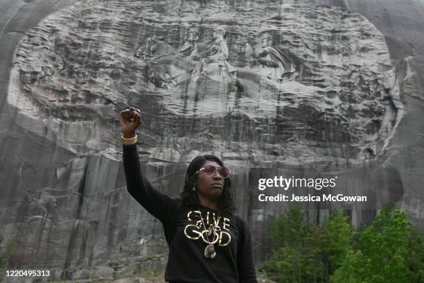 Lahahuia Hanks holds up a fist in front of the Confederate carving at Stone Mountain Park during a Black Lives Matter protest on June 16, 2020 in...