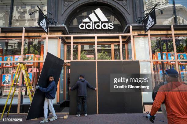 Workers remove plywood panels from boarded up windows of an Adidas AG store in San Francisco, California, U.S., on Tuesday, June 16, 2020. San...