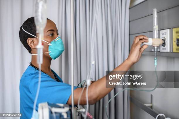 african female nurse adjusting medical oxygen equipment - medical oxygen equipment stock pictures, royalty-free photos & images