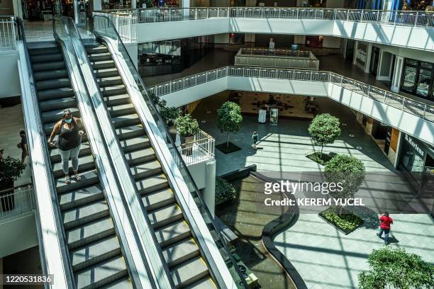 Woman wearing a facemask rides down the escalator at the Mall of America on June 16, 2020 in Bloomington, Minnesota, after some of the shops at the...
