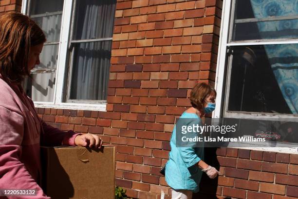 Dr Jane Carrick, a volunteer at St Paul's Anglican Church Parish Pantry speaks with a local man through his window in Enfield on April 23, 2020 in...