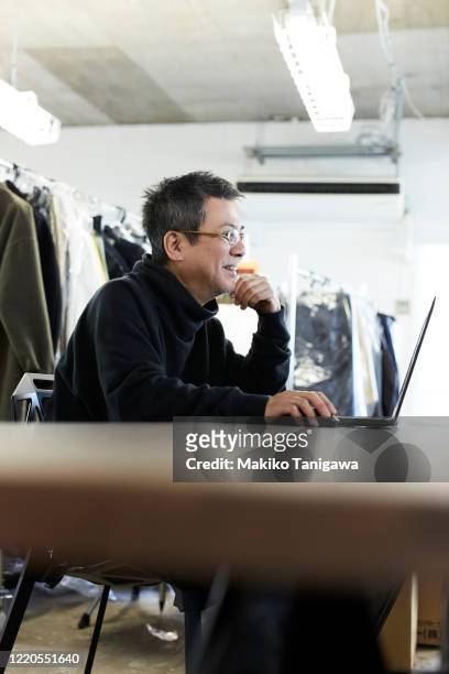 mature japanese man at apparel maker's design office - creative director stock pictures, royalty-free photos & images