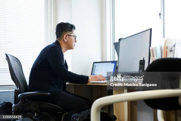 mature japanese business man working in his office - desktop pc stock pictures, royalty-free photos & images
