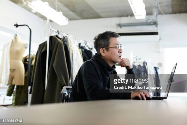 mature japanese man at apparel maker's design office - fashion director stockfoto's en -beelden