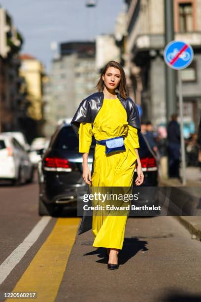 Landiana Cerciu wears a yellow dress, a blue belt bag, a black leather cape, outside Max Mara, during Milan Fashion Week Fall/Winter 2020-2021 on...