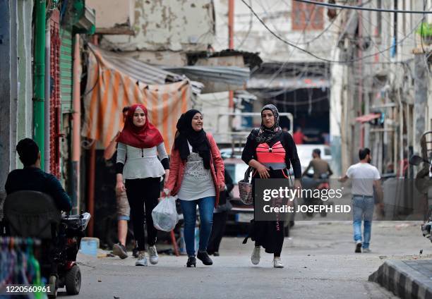 Women walk along an alley in the Bab al-Tabbaneh neighbourhood of Lebanon's northern city of Tripoli on June 3, 2020. - Thousands of residents of...