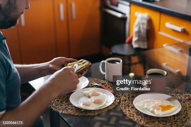 a man preparing homemade fried eggs for breakfast - untar de mantequilla fotografías e imágenes de stock