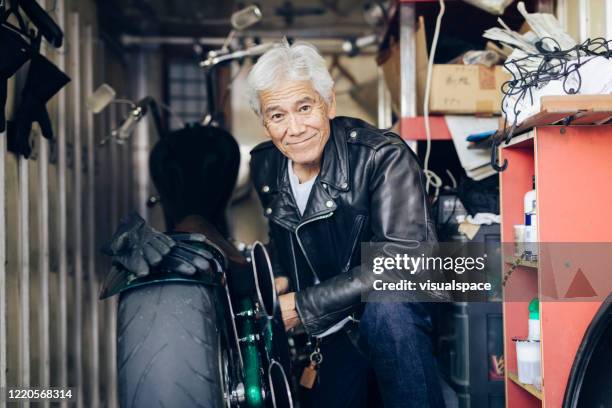 happy senior man repairing a motorcycle - motorcycle workshop stock pictures, royalty-free photos & images