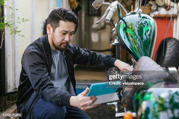man repairing a motorcycle with the help of online videos - youtube stock pictures, royalty-free photos & images