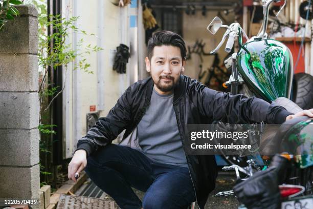 portrait of asian biker in front of his small workshop - motorcycle man stock pictures, royalty-free photos & images