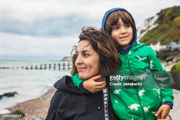 a young mother and her cute little son are walking by a sea - british culture walking stock pictures, royalty-free photos & images