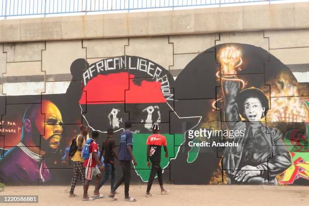 Group of youth walks past mural depicting of Anti-racism, liberty of Africa continent with image of Kemi Seba and Winnie Mandela painted by a...