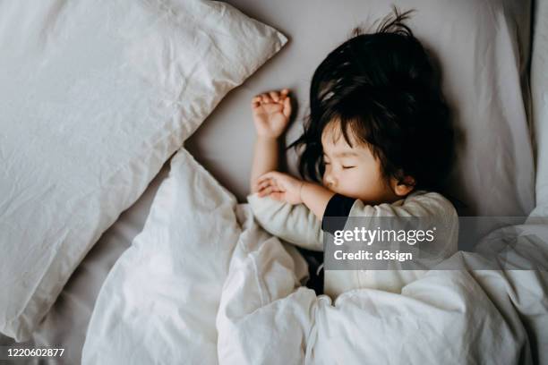 asian toddler girl sleeping soundly on traditional japanese style futon, laid on tatami mat floor at home - sleeping toddler bed stock pictures, royalty-free photos & images