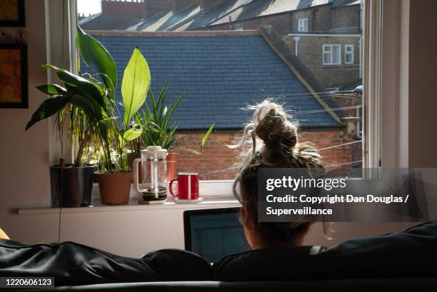 attractive casual hippie woman working from home in her pyjamas - messy hair bun stock pictures, royalty-free photos & images