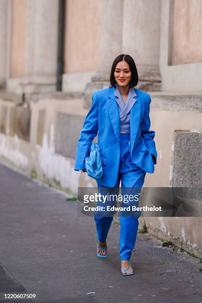Tiffany Hsu wears a blue oversized blazer jacket, a blue leather The Pouch Bottega Veneta bag, blue pants, sandals, outside Koche x Pucci, during...
