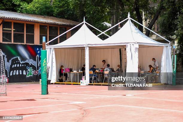 Two high school student pass the Baccalaureat examination on June 17, 2020 under a tent set up in the yard at the J. F. Kennedy High School in Rome,...