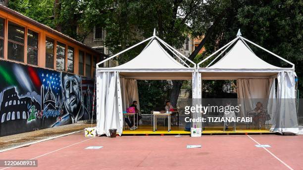 High school students pass the Baccalaureat examination on June 17, 2020 under a tent set up in the yard at the J. F. Kennedy High School in Rome, as...