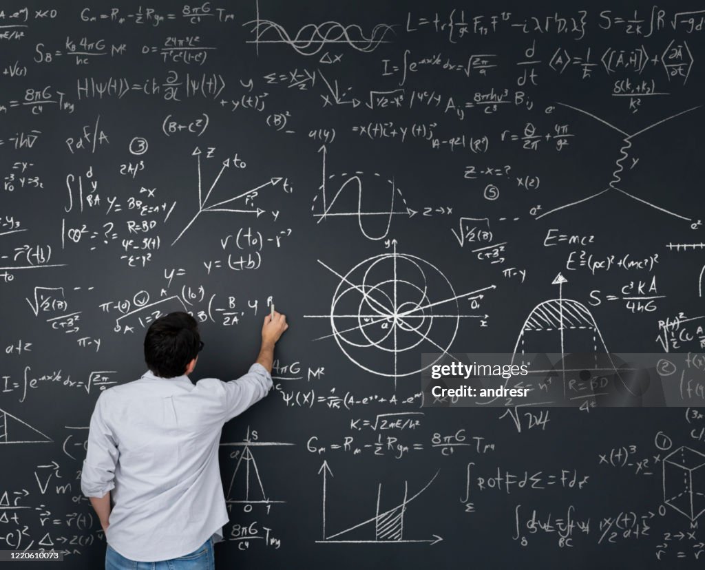 Physiklehrer schreibt mathematische Gleichungen auf einer Tafel