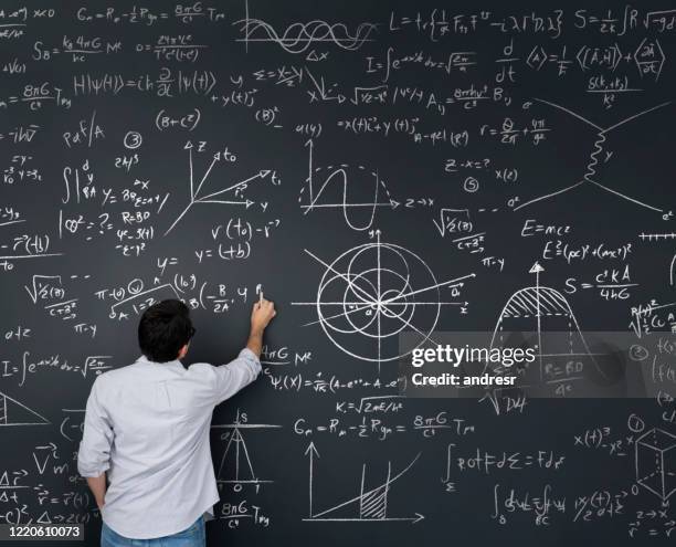 physiklehrer schreibt mathematische gleichungen auf einer tafel - physik stock-fotos und bilder