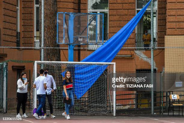 High school students wait during the Baccalaureat examination on June 17, 2020 under in the yard at the J. F. Kennedy High School in Rome, as the...