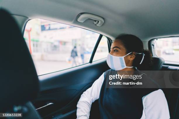 woman traveling by taxi during covid-19 pandemic - medical transportation stock pictures, royalty-free photos & images