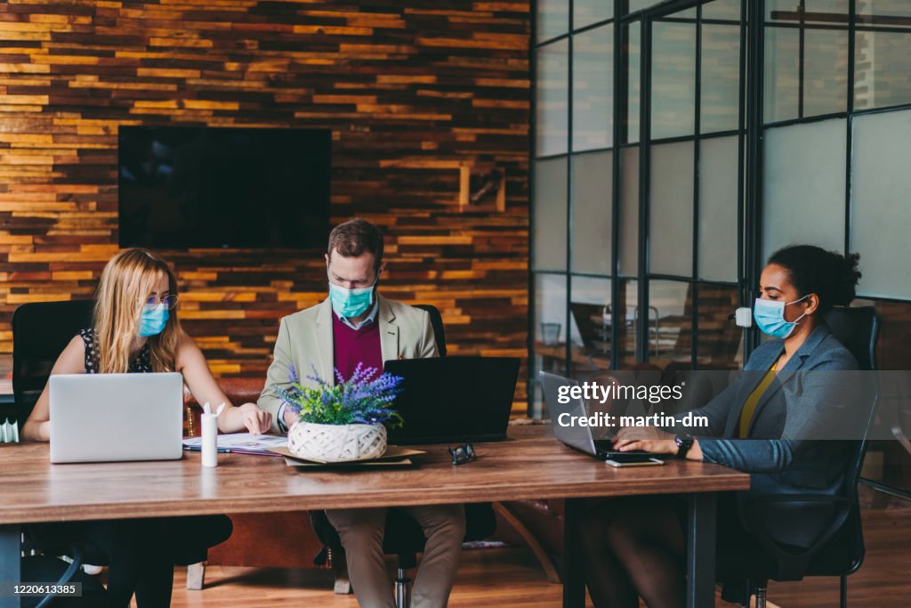 Hommes d’affaires travaillant avec des masques dans le bureau pendant la pandémie de COVID-19