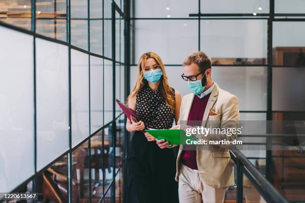 business people wearing face masks at work during covid-19 pandemic - protective face mask office stock pictures, royalty-free photos & images