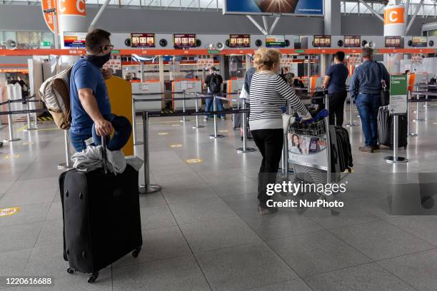 Passengers keep distance as they wait for check-in of their flight to Frankfurt with Lufthansa as Polish government reinstalls some of the...